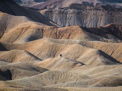two hikers stand in a field of dunes made up of river sediments